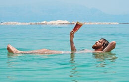 Man reading while floating in ocean