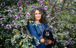 Woman holding dog standing by flowers