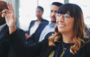 Shot of a young businesswoman sitting in the audience of a business conference and raising her hand