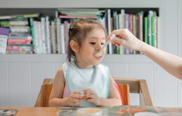 Woman feeding child with spoon