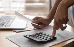 African woman holding paper bills using calculator