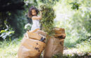 Girl putting pile of weeds into lawn bag