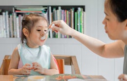 Woman feeding child with spoon