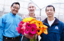 Three men holding Gerbera daisies