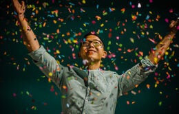 Person celebrating with raised arms and confetti