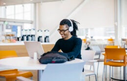student working on a computer in a dining hall
