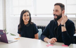 Woman and man laughing while sitting at a conference table