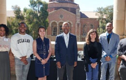 President Drake standing, smiling with a diverse group of UCLA students