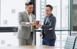 Men in suits talking and looking at a cellphone