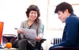 Two people sitting in an office talking about a paper