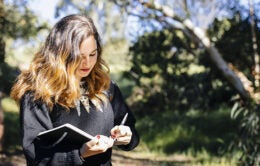 A student strolls a leafy section of the UCLA campus.