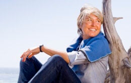 Woman leaning against a large piece of driftwood