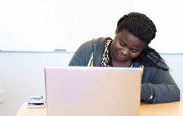 Woman working at laptop with calculator at UC Merced
