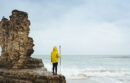 UC Santa Cruz student researcher standing by the ocean in a yellow raincoat