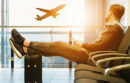 Man relaxing with feet on suitcase watching airplane at the airport