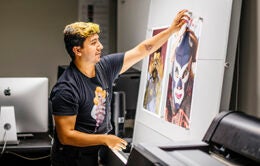 student placing large-format photographs on a wall