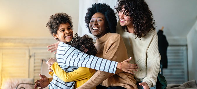 Happy lesbian multiethnic couple with childen at home.