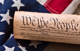 United States Constitution, rolled in a scroll on a vintage American flag and rustic wooden board