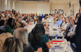 EVP/COO Rachael Nava (standing) and UC leaders visit with UCPath staff.