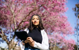 Woman standing in front of flowering tree holding a digital tablet