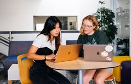 Two women working together at laptop computers