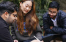 UC graduate students working around a tablet together outdoors