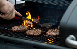 Person grilling burgers on a gas grill