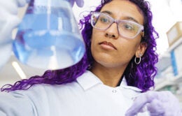 Purple-haired scientist holding a beaker