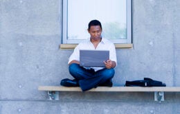 Man sitting on a bench using a laptop