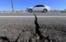 Car driving over damaged sidewalk