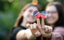 Portrait of two women holding out their hands together with the I voted stickers attached to their fingers for the viewer to see. Their fingers form the v for victory and peace sign.