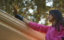 Woman cleaning pine needles from her gutters