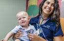 Smiling nurse holding baby