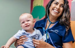 Smiling nurse holding baby