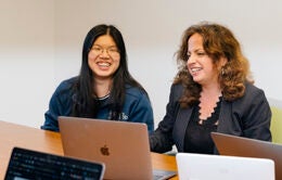 Women working side by side on laptop computers