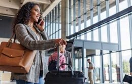 Waist-up side shot with blurred background of an attractive mid-adult Latin-American business woman talking on the phone with her husband as she goes for a business trip soon.