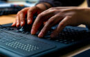 Modern Braille display device connected to a computer, with a visually impaired person using it to read digital text.