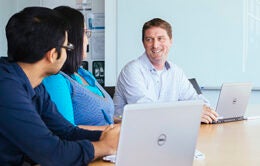 Three people talking in a conference room at UCPath