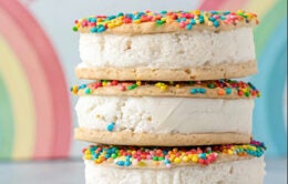 Ice cream sandwiches with rainbow sprinkles and a rainbow in the background
