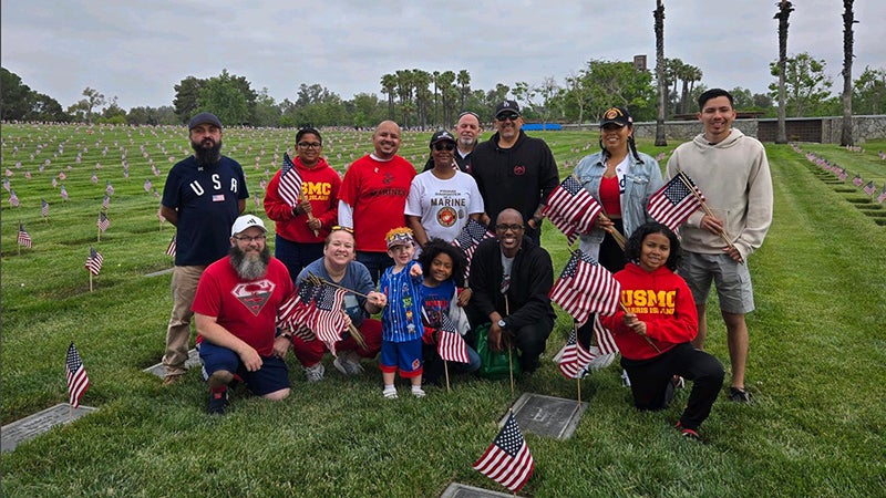 Group of people holding American flags in a cemetery