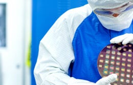 Scientist in safety suit holding giant chip