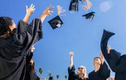 UC graduates throwing their caps into the air