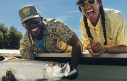 Two very excited men holding a large fish in a boat