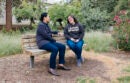 Two people talking on a bench outside