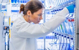 Scientist in white lab coat inspecting equipment