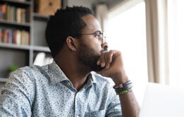 Thoughtful serious african professional business man sit with laptop thinking of difficult project challenge looking for problem solution searching creative ideas lost in thoughts at home office desk