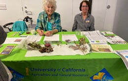two women staffing table and community and connection fair