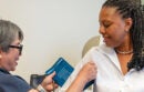 Uniformed woman checking another woman's blood pressure