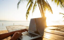 person working on the sea at sunset with a computer