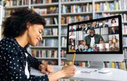 African American happy female student, learning distantly, watches an online lecture, taking notes, multiracial smiling people on a computer screen, virtual communication